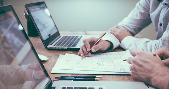 Zwei Männer mit Laptop am Tisch