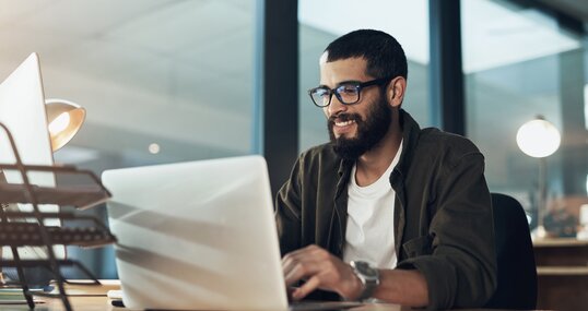 Smile, work and a businessman with a laptop for an email, communication or online coding. Happy, programming and a male programmer typing on a computer for web or software development in an office