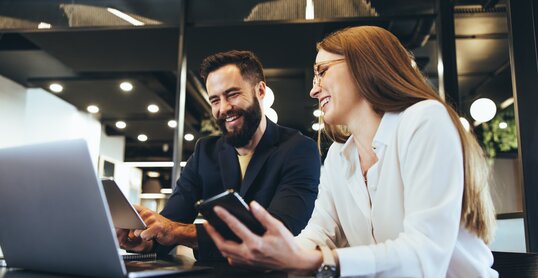 Smiling entrepreneurs using wireless technology together