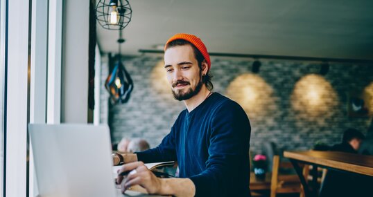 Positive caucasian male checking news from networks working remotely on publicity area, man freelancer reading information on web page looking on screen of laptop computer connected to wifi internet