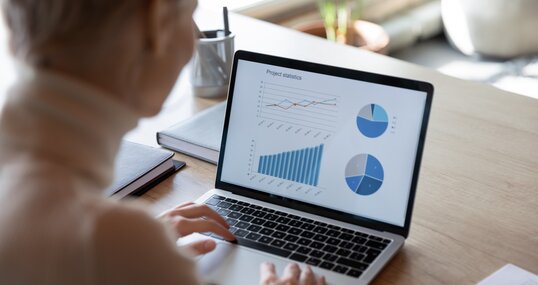 Charts, graphs, analysis sales information on laptop screen view over financier shoulder, visual representation of financial data, using helpful app for make analyze easier. Project statistics concept