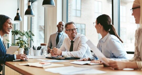 Diverse businesspeople laughing during a meeting around an offic