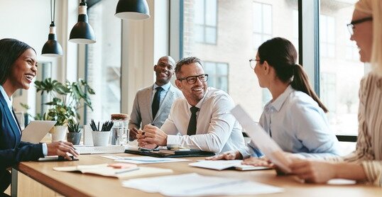 Diverse businesspeople laughing during a meeting around an offic