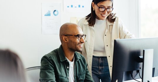 Web developers using a computer together in an office