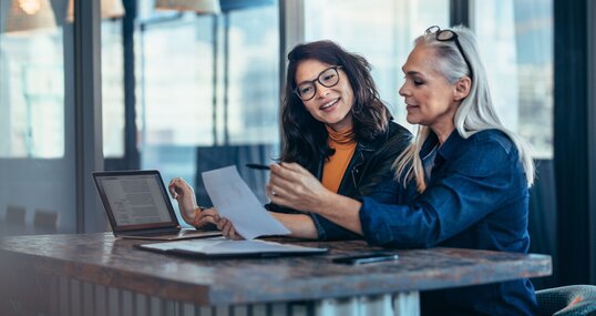 Two women analyzing documents at office