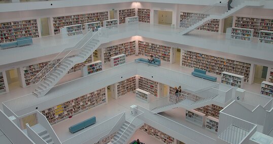 Ein Gang mit deckenhohen Regalen zu beiden Seiten, in denen ungeordnet Bücher gestapelt sind.