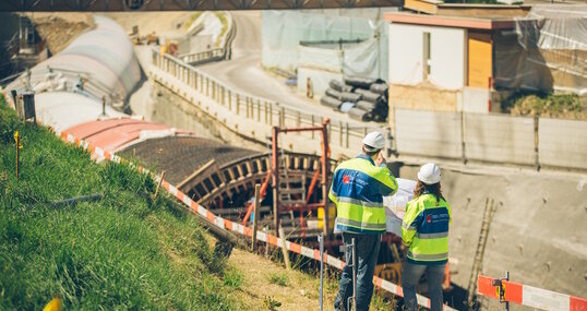 Zwei Bauarbeiter begutachten eine Baustelle