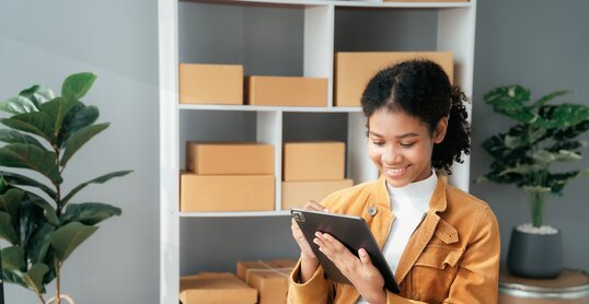 Junge Frau sitzt am Schreibtisch und arbeitet am Tablet